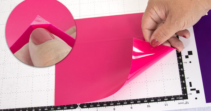 Insert your iron-on foil into the cutting machine with the transparent plastic side facing down. Peel off the foil slightly at the corner to find the right side.